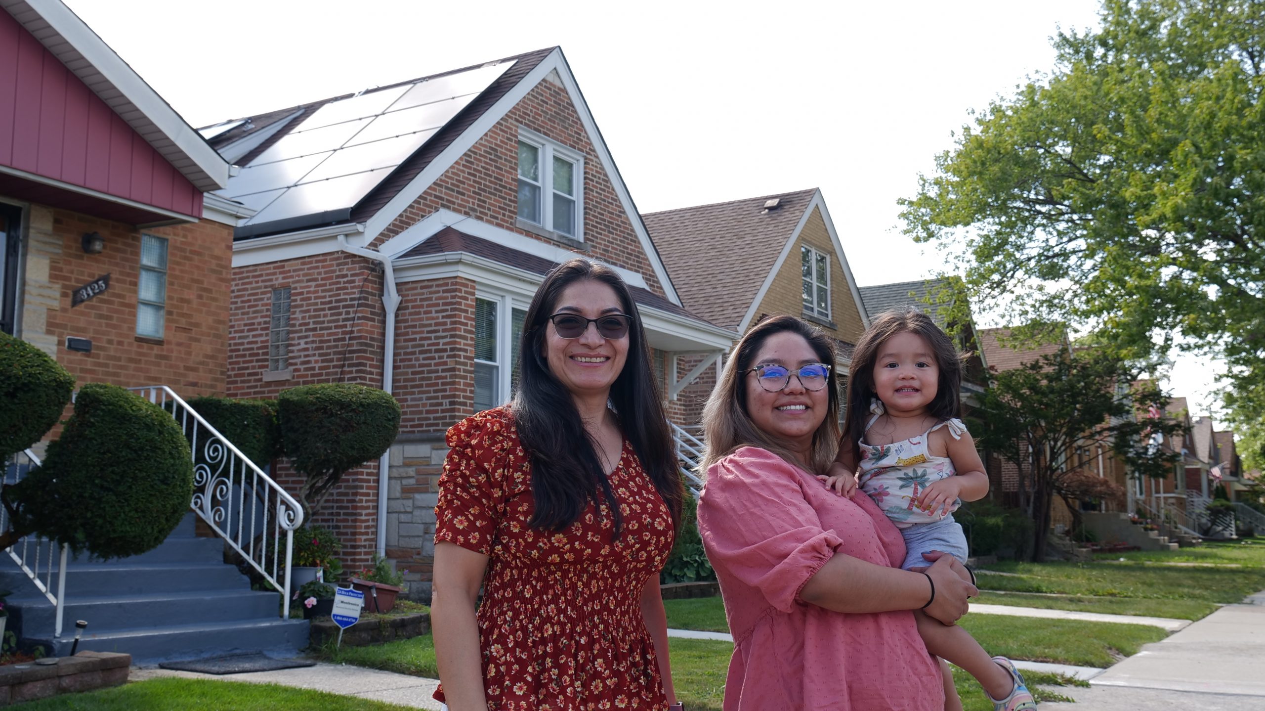 ILSFA family smiling in front of their newly installed solar panels